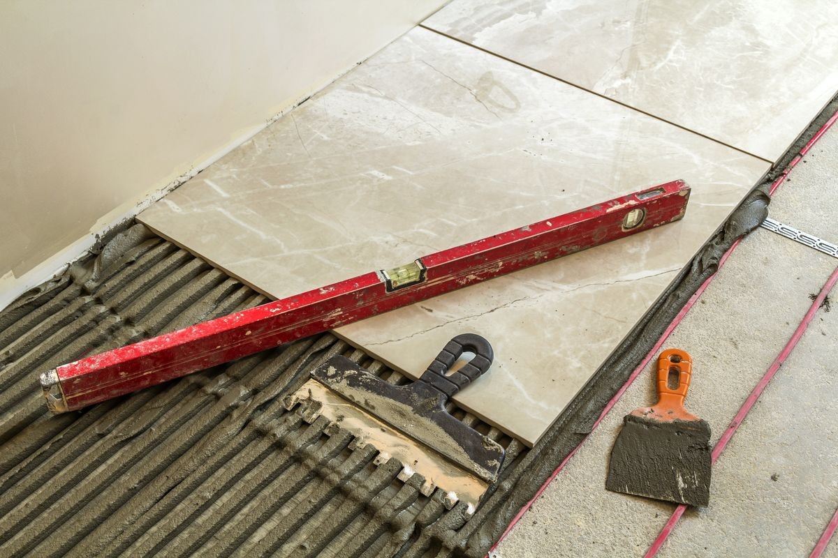 Ceramic tiles and tools for tiler. Floor tiles installation. Home improvement, renovation - ceramic tile floor adhesive, mortar, level